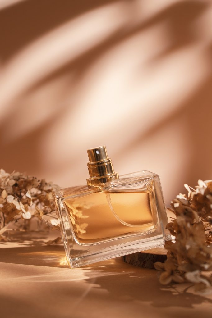 Transparent bottle of perfume on a beige background