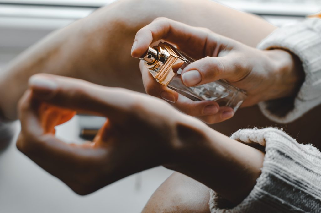 Young woman sprinkles perfume on her wrist. Perfume in a woman's hand